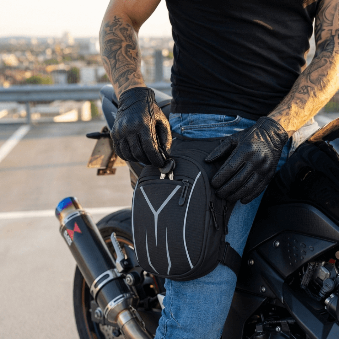 Person sitting on a motorcycle with the wearing the havoc leg bag, wearing black gloves and a black shirt.